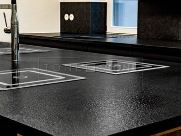 Detail varného ostrůvku ze žuly Nero Assoluto Zimbabwe (trattato), v pozadí kuchyňská deska a parapet ze stejného přírodního kamene. Zakázková výroba TONE OF STONE 