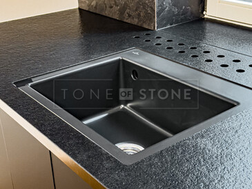 Detail kuchyňské pracovní desky a parapetu ze žuly Nero Assoluto Zimbabwe (trattato). Součástí pracovní desky je i dřez se spodní montáží a integrované průduchy pro skrytá topení za linkou. Zakázková výroba TONE OF STONE.  