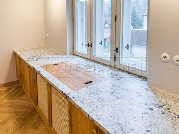 Kuchyňská pracovní deska z indické žuly Colonial White v úpravě satén. Do kuchyňské desky je vsazen dřez se spodní montáží a zabudovaný projektor. Integrovaný parapet s průduchy pro proudění teplého vzduchu z topení je součástí pracovní desky. Zakázková výroba TONE OF STONE. Kuchyňská pracovní deska z indické žuly Colonial White v úpravě satén. Do kuchyňské desky je vsazen dřez se spodní montáží a zabudovaný projektor. Integrovaný parapet s průduchy pro proudění teplého vzduchu z topení je součástí pracovní desky. Zakázková výroba TONE OF STONE.