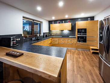 Pracovní kuchyňská deska a obklad stěn za kuchyňskou linkou z přírodního kamene - žula STELL GREY s kartáčovaným povrchem, deska ve tvaru písmene U. Zakázková výroba TONE OF STONE.