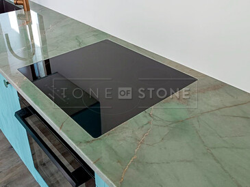 Detail kuchyňské pracovní desky zkvarcitu Jadore a varné desky zabudované do roviny. V pozadí dřez se spodní montáží. Zakázková výroba kamenictví TONE OF STONE.   