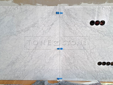 První dvě desky mramoru Bianco Carrara jsou již připevněny na stěně. Na pravé desce jsou umístěny výřezy na zásuvky a pro televizi. Zakázková výroba, kamenictví TONE OF STONE.