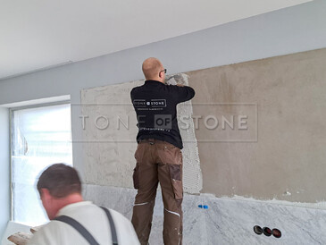 Práce při obložení stěny přírodním mramorem Bianco Carrara