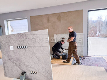 Práce při obložení stěny přírodním mramorem Bianco Carrara