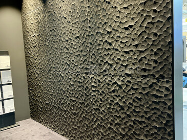 Nasvícený obklad zdi černým přírodním kamenem s hrubou povrchovou úpravou.