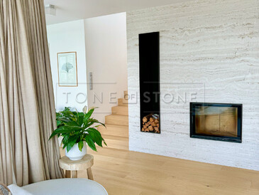 Minimalistický obývací pokoj s krbem obloženým přírodním kamenem Travertino Romano Classico v domě Zorky a Míry Hejdových. Zakázková výroba na přání pro manžele Hejdovy. Vyrobeno zakázkovým kamenictvím TONE OF STONE.