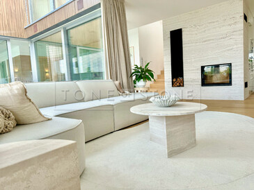 Luxusní a útulný obývací pokoj manželů Hejdových s krbem obloženým přírodním travertinem a designovým stolkem, který dokonale ladí s celkovým prostorem. Zakázková výroba na přání pro manžele Hejdovy. Vyrobeno zakázkovým kamenictvím TONE OF STONE.