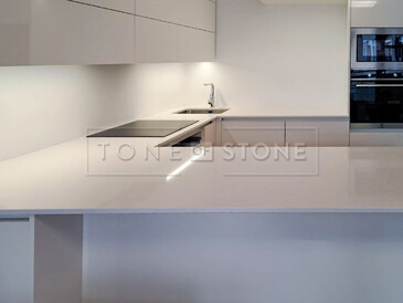 Bílá kuchyně s kamennou pracovní deskou z umělého kamene Technistone Noble Supreme White. Zakázková výroba TONE OF STONE. 