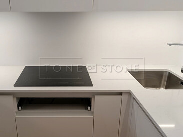 Do bílé kamenné pracovní desky z materiálu Technistone Noble Supreme White jsem instalovali varnou desku s horní montáží a dřez se spodní montáží včetně výřezu na baterii. Zakázková výroba TONE OF STONE. 