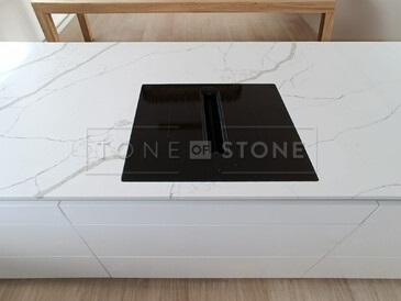 Varná deska zapuštěná do roviny s integrovaným odsavačem jako součást pracovní desky z materiálu Crystal Calacatta Silva. Zakázková výroba TONE OF STONE.