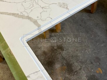 Detail výřezu pro varnou desku s montáží do roviny - TechniStone Crystal Calacatta Silva. Zakázková výroba kamenictví TONE OF STONE.