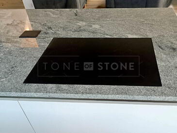 Varná deska zapuštěná do roviny a integrované elektrické zásuvky jako součást moderní kuchyně s kuchyňskou deskou ze žuly Viscount White (Viscont White). Zakázková výroba TONE OF STONE. Varná deska zapuštěná do roviny a integrované elektrické zásuvky jako součást moderní kuchyně s kuchyňskou deskou ze žuly Viscount White (Viscont White). Zakázková výroba TONE OF STONE.