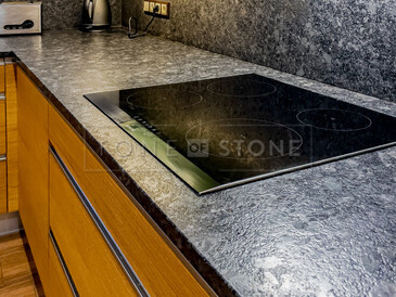 Žulová pracovní deska s kartáčovanou povrchovou úpravo Steel grey s obkladem stěny a varnou deskou s horní montáží.  Zakázková výroba TONE OF STONE.