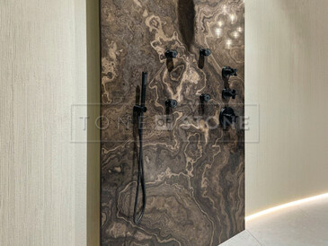 Obklad stěny sprchového koutu v koupelně z přírodního kamene. 