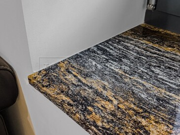 Tmavý kamenný parapet ze žuly Magma Black se svou charakteristickou žilkovanou kresbou plnou černých a zlatých tónů