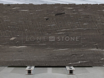 Hnědá kamenná deska Brown Silk s vodorovným žilkováním v šedých a bílých tónech.