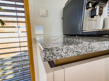 Precizní opracování hran kamenné kuchyňské desky ze žuly Viscount White. Pro tuto realizaci byl zvolen typ opracování H1.