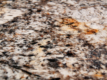 Detail struktury přírodní žuly Amarone se zrnitou texturou obsahující šedou, bílou, černou a žlutou barvu