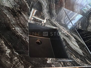 Kamenná pracovní deska ze žuly Agata Black včetně kamenného obkladu za kuchyňkou deskou, jejíž součástí je i dřez se spodní montáží