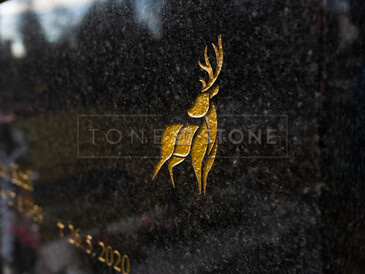 Detail vypískovaného jelena ve zlaté barvě na desce z přírodního kamene - žula Impala. Hřbitovní architektura, zakázková výroba TONE OF STONE.
