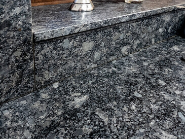 Kamenná kuchyňská deska a obklad stěn za kuchyňskou linkou s přechodem na obložení okenního parapetu, přírodní kámen - Žula STEEL GRAY s kartáčovaným povrchem, detail přechodu