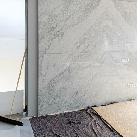 Mramor Bianco Carrara kr&aacute;tce po mont&aacute;ži na stěnu, obklad m&aacute; rozměr 260x332 cm. Zak&aacute;zkov&aacute; v&yacute;roba, kamenictv&iacute; TONE OF STONE.