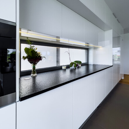 Bílá lesklá kuchyně s černou žulovou pracovní deskou z přírodního kamene Nero Assoluto Zimbabwe s kartáčovanou povrchovou úpravou