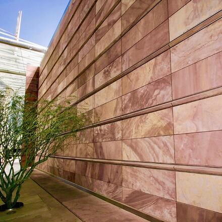 Fasáda budovy obložená přírodním kamenem Las Vegas Rock s jemnými barevnými přechody v odstínech hnědé a růžové. Zakázkové kamenictví TONE OF STONE. Fasáda budovy obložená přírodním kamenem Las Vegas Rock s jemnými barevnými přechody v odstínech hnědé a růžové. Zakázkové kamenictví TONE OF STONE.