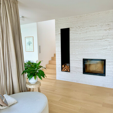 Minimalistický obývací pokoj s krbem obloženým přírodním kamenem Travertino Romano Classico v domě Zorky a Míry Hejdových. Zakázková výroba na přání pro manžele Hejdovy. Vyrobeno zakázkovým kamenictvím TONE OF STONE.