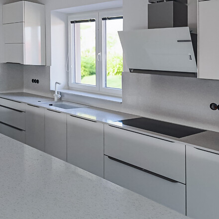 Kuchyňská pracovní deska z materiálu Technistone doplněna o zádový obklad a parapet.