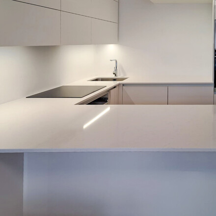 Bílá kuchyně s kamennou pracovní deskou z umělého kamene Technistone Noble Supreme White. Zakázková výroba TONE OF STONE.