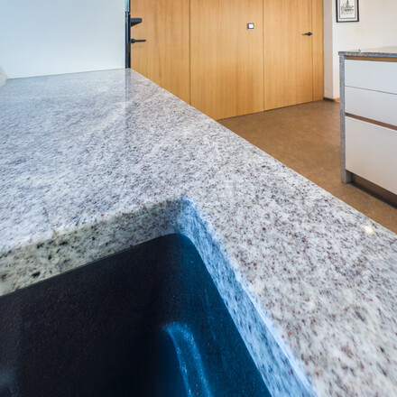 Kamenná kuchyňská deska ze žuly Kashmir Silver s dřezem se spodní montáží.