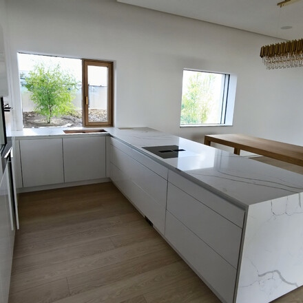 Modern&iacute; b&iacute;l&aacute; kuchyňsk&aacute; linka s pracovn&iacute; deskou Technistone Crystal Calacatta Silva. Zak&aacute;zkov&aacute; v&yacute;roba TONE OF STONE.