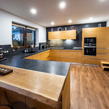 Kuchyňská deska z kartáčované žuly Steel grey doplněná o obklad stěny a kamenný parapet. Zakázková výroba TONE OF STONE.