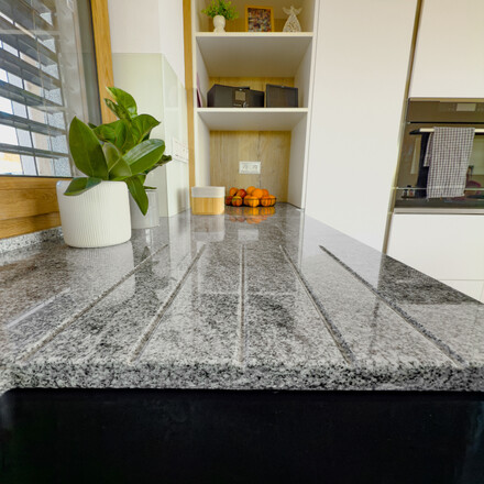 Vyfrézované odkapové drážky do kamenné kuchyňské desky ze žuly Viscount White jsou elegantním řešením pro odvod přebytečné vody zpět do dřezu.