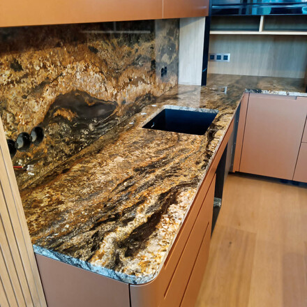 zlatá kuchyňská deska ze žuly Magma Gold včetně kamenného obkladu za kuchyňskou deskou a dřezu se spodní montáží