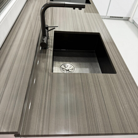 Šedá kuchyňská deska z šedého přírodního kamene Grey Veneer - dřez se spodní montáží, kamenná parapet součástí kuchyňské desky